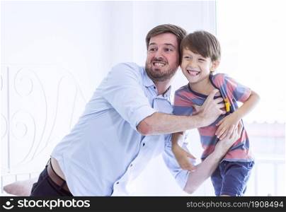Caucasian father and son are happy and playing together at home. Education and Family concept.