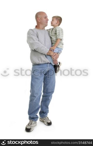 Caucasian father and son in casual attire standing over white. Father holding son in arms.