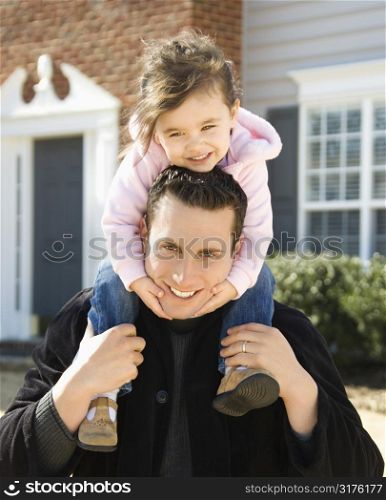 Caucasian father carrying daughter on shoulders.