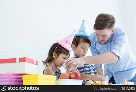 Caucasian father celebrating his children&rsquo;s birthday while little boy and girl are very happy. Party and family concept.