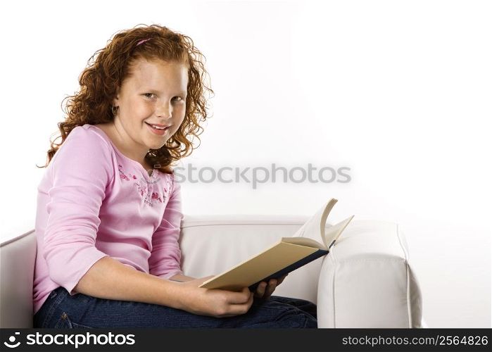 Caucasian female child sitting reading book.