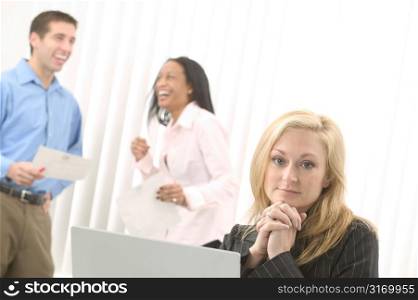 Caucasian Female Manager Sitting Behind A Laptop Computer While Her Team Laughs In The Background
