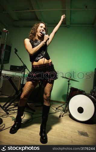 Caucasian female singning into microphone.