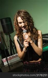 Caucasian female singning into microphone.