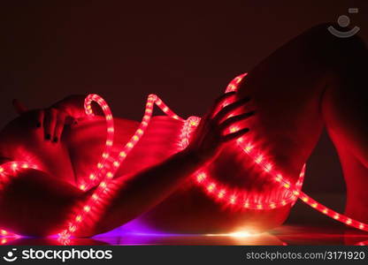 Caucasian female young adult nude lying on back wrapped in rope light.