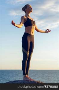 caucasian fitness woman practicing yoga. young caucasian fitness woman practicing yoga at sea shore