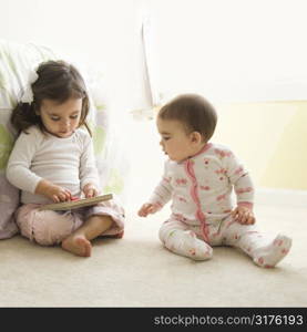 Caucasian girl children sitting on bedroom floor looking at book.