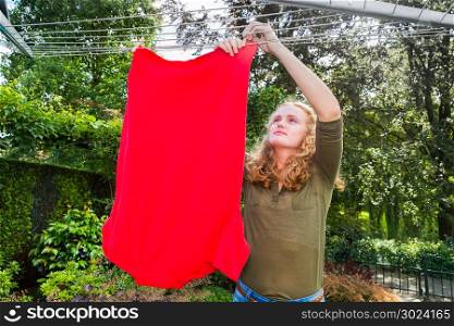 Caucasian girl hangs clothes at washing line outdoors