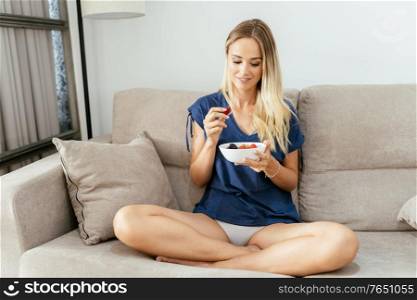 Caucasian girl in casual clothes eating an vegan appetizer with nuts, raspberries and blackberries. Concept of healthy diet.. Young woman eating an vegan appetizer with nuts, raspberries and blackberries.