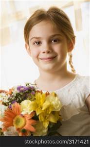 Caucasian girl smiling at viewer with bouquet of flowers.