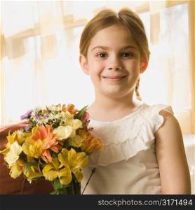 Caucasian girl smiling at viewer with bouquet of flowers.