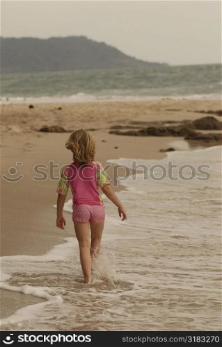 Caucasian girl walking down beach