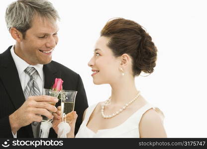 Caucasian groom and Asian bride toasting with champagne glasses.