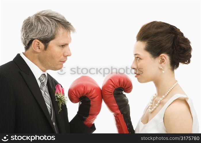 Caucasian groom and Asian bride wearing boxing gloves.