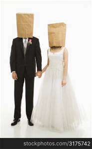 Caucasian groom and Asian bride with brown paper bags over their heads.