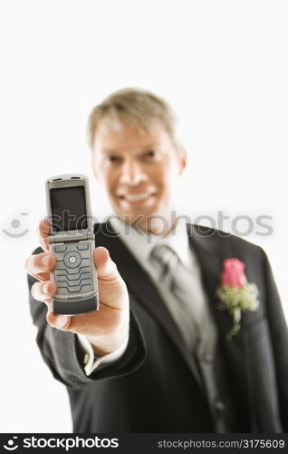 Caucasian groom holding out his cellphone towards viewer.