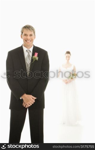 Caucasian groom in foreground and Asian bride in background.