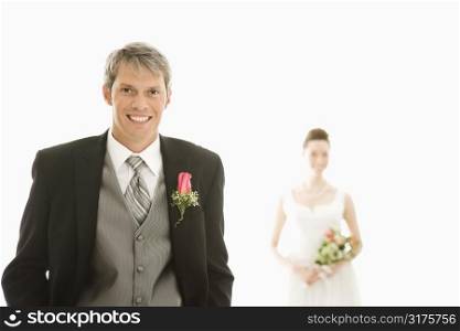 Caucasian groom in foreground and Asian bride in background.