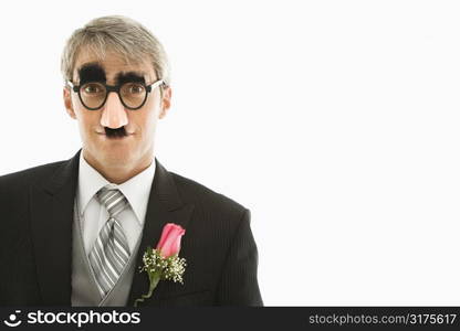 Caucasian groom wearing groucho glasses making eye contact.