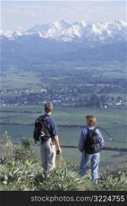 Caucasian Hikers Standing On A Point Overlooking A Mountain Valley