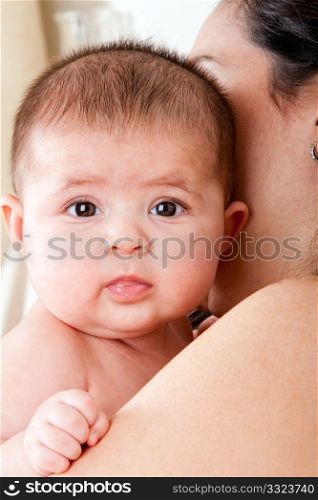 Caucasian Hispanic Latina mother holding cute baby. Infant face with twinkly eyes and drooling.