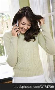Caucasian/Hispanic young woman on cell phone smiling.
