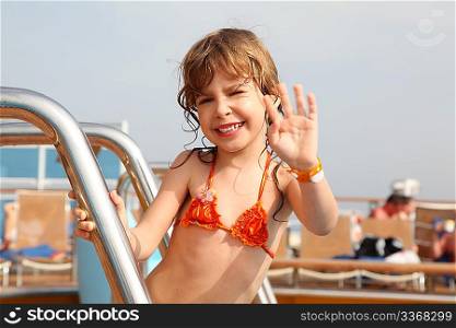 caucasian little girl standing on cruise ship, smiling and waving hand focus on face