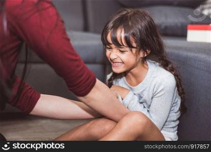 Caucasian little girl tickled by mother in living room. People lifestyle and kids concept.