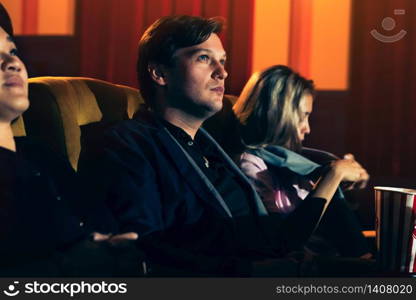 Caucasian lover and woman sitting next to them enjoying to watch movie