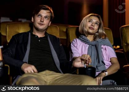 Caucasian lover enjoying to watch movie and eating popcorn together in the cinema