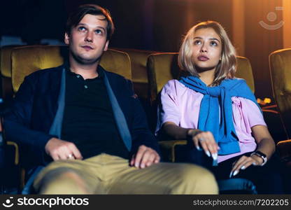 Caucasian lover enjoying to watch movie and eating popcorn together in the cinema