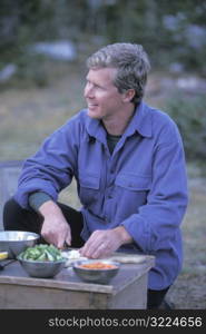 Caucasian Male Camper Preparing A Meal And Smiling