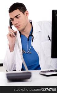 Caucasian male doctor sitting at the desk with computer talking over phone in white background