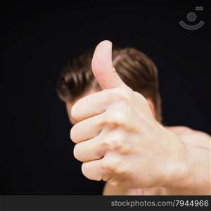 Caucasian male showing thumbs up covering face isolated on black