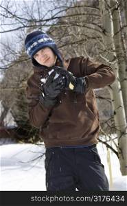Caucasian male teenager making snowball in winter setting.