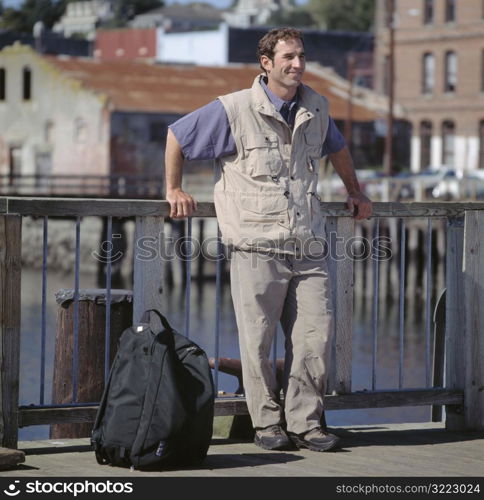 Caucasian Male Traveler Standing On A Bridge And Smiling