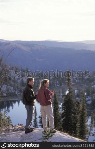 Caucasian Man And Woman Standing On A Rock Overlooking A Mountain Stream
