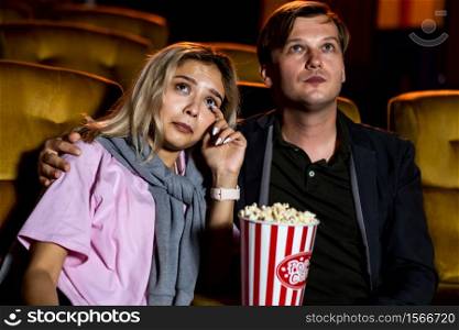 Caucasian man and woman watching a sad movie and his girlfriend crying