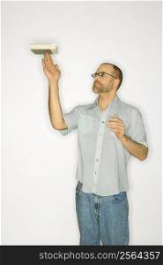 Caucasian man balancing book on fingers standing against white background.