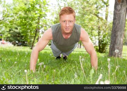 Caucasian man doing a push up in park against blur background