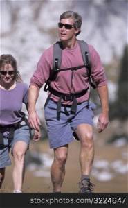 Caucasian Man Hiking With A Woman Through A Rocky Valley