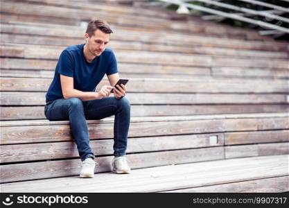 Caucasian man is reading text message on mobile phone in the park and searching information on smartphone. Man is reading text message on mobile phone while walking in the park