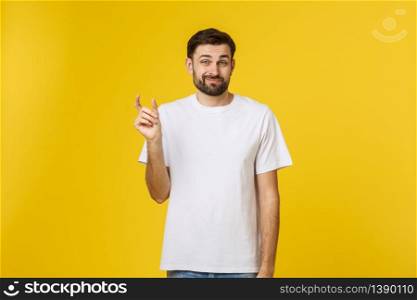 Caucasian man show small size by fingers demonstrate tiny measure, tell about little decreased prices. Studio shot yellow wall.. Caucasian man show small size by fingers demonstrate tiny measure, tell about little decreased prices. Studio shot yellow wall
