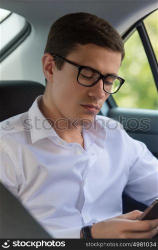 Caucasian man sitting in car with mobile phone in hand and texting
