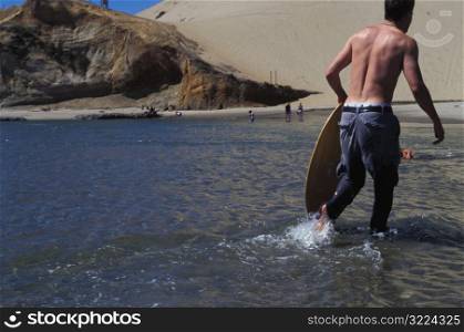 Caucasian Man Skim Boarding On The Beach