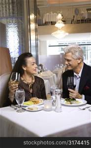 Caucasian mature adult male and prime adult female sitting at restaurant table.