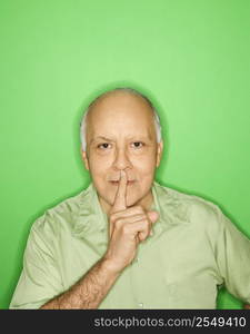 Caucasian mature adult male holding finger to mouth.