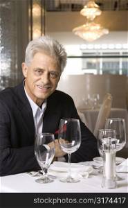 Caucasian mature adult male sitting at restaurant table looking at viewer smiling.