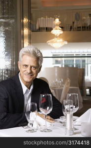 Caucasian mature adult male sitting at restaurant table looking at viewer smiling.