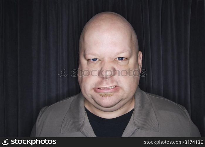 Caucasian mid adult bald man looking at viewer with angry expression.